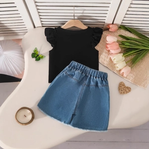Dettaglio di top nero con maniche a farfalla e pantaloncini in denim con orlo a frange