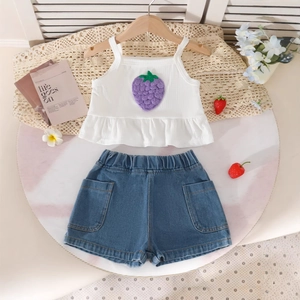 Détail de la broderie fraise sur le haut blanc à volants et le short en jean