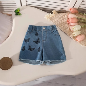 Detail of light blue denim shorts with butterfly embroidery and raw hem edges