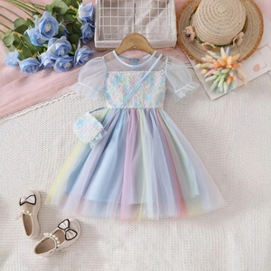 Flat lay of rainbow sequin tulle girl's dress with matching floral bag and pearl shoes