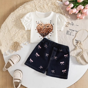 Flat lay of girl's white heart-print ruffle tee and denim shorts with pink bow embroidery