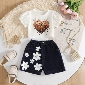 Flat lay of girl's summer outfit with heart print t-shirt and floral denim shorts