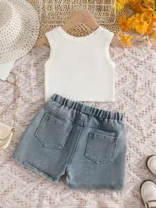 Flat lay of girl's white sleeveless top and denim shorts with summer accessories