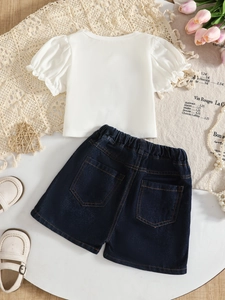 Flat lay of girl's white puff sleeve top and denim shorts set with elegant accessories