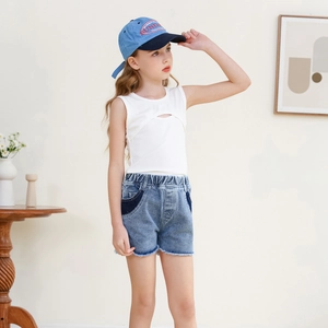 Detailed look of girl's summer outfit with a white cutout vest and frayed denim shorts