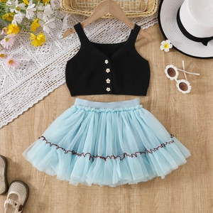 Dettaglio gilet nero in maglia con bottoni a margherita e gonna in tulle azzurro