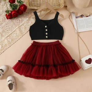 Dettaglio della gonna tutù in tulle bordeaux con gilet in maglia e bottoni margherita