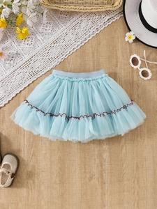 Gonna tutu multistrato celeste per bambina con ricamo ondulato su sfondo di legno