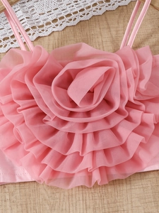 Rosa Kinderoberteil mit gestuften Netzblumen und Rüschen auf hellem Holzgrund