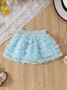 Flat lay of light blue tutu skirt with layered ruffles and elastic waist on wood floor
