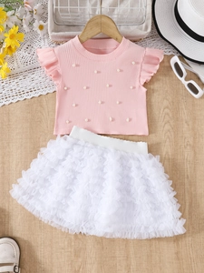Detailed view of pink knitted top with faux pearls and white layered tulle tutu skirt