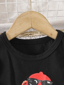 T-shirt noir en coton pour fille avec motif dessin animé rouge sur cintre en bois