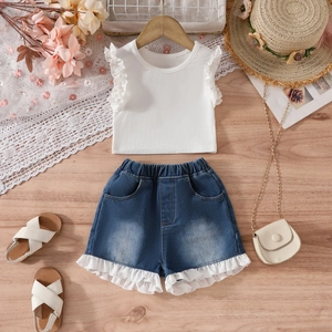 Ensemble d'été pour fille avec haut à volants et short en jean sur fond de bois naturel