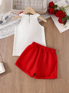 Kids summer floral lace top and red shorts two-piece set flat lay on wooden floor