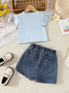 Girls summer two-piece set featuring light blue ruffled top and denim shorts on beige rug