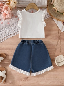 Ensemble été fille avec haut à volants blanc et short en jean sur fond en bois
