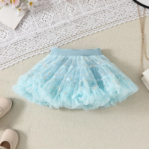 Detailed flat lay of light blue tulle tutu skirt with gold stars and chic accessories