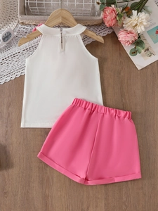 Girls summer two-piece outfit with white halter top and pink shorts on a wooden hanger