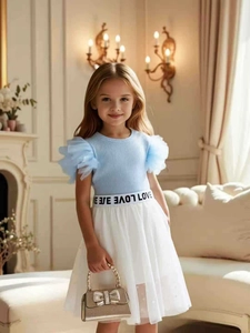 Dettaglio di maglia a maniche in rete e gonna in tulle a pois per bambine con cintura