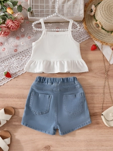 Flat lay of girl's strawberry white camisole and embroidered denim shorts summer set