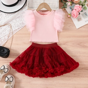 Detail of pink ruffled top and burgundy tutu skirt set with accessories on wood