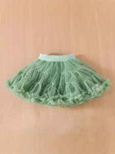 Sage green multilayered tulle tutu skirt for baby girls on a natural wood background