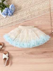 Girls layered tutu skirt with beige mesh and light blue ruffled hem on wood floor