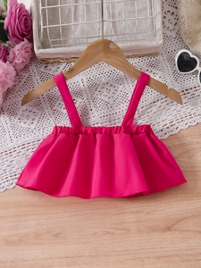 Girl's summer outfit with hot pink ruffle camisole top and elastic hem on wooden background