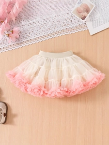 Fluffy beige and pink tiered mesh tutu skirt for baby girls on light wood background