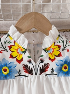 Detail of baby girl floral top featuring ruffled high collar and vibrant flower prints