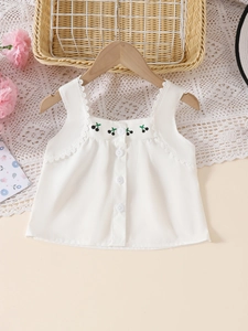Détail d'un haut sans manches blanc pour fille avec broderie cerise et bordure en dentelle