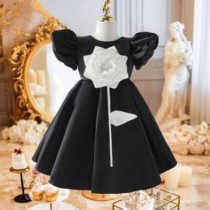 Detail eines eleganten schwarzen Satinkleides für Kinder mit großer weißer 3D-Rose