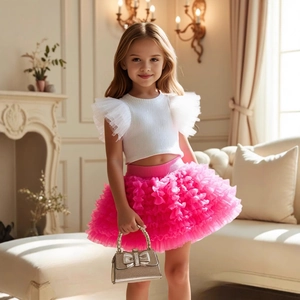 Close-up of girls' white knit top with organza ruffles and bright pink layered tutu skirt
