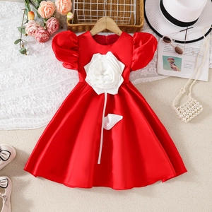 Detail eines roten Satin-Mädchenkleids mit weißer 3D-Rose und Puffärmeln am Kleiderbügel