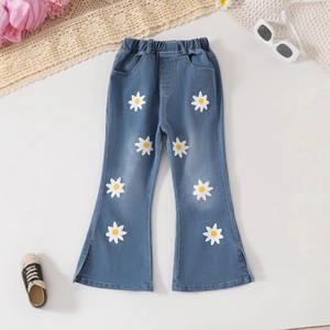 Detail of girls' flared denim pants with daisy prints and side slit leg openings