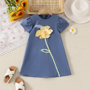 Dettaglio di abito blu per bambine con ricamo di fiori gialli e accessori estivi