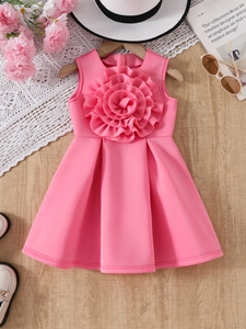 Detailed view of pink sleeveless girl's dress with a large 3D floral accent on a flat lay