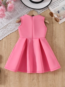 Detail of pink sleeveless flower girl dress with pleated A-line skirt on wooden background