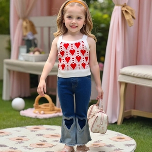 Detail von gestricktem weißen Top mit roten Herzen und Jeans-Schlaghose mit Herz-Ausschnitt
