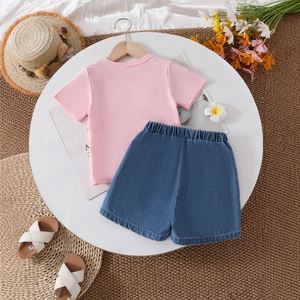 Flat lay view of a girls' pink t-shirt and denim shorts set with summer accessories