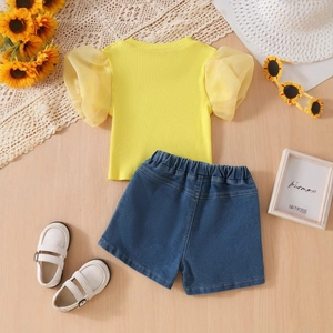Flat lay of girl summer outfit with puff sleeve top and denim shorts on wooden background
