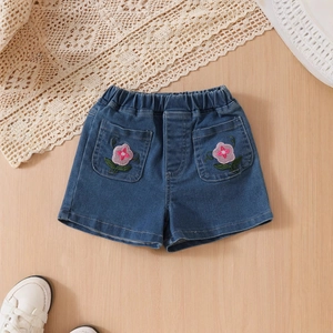 Detail of girl's denim shorts featuring embroidered flowers and an elastic waistband