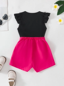 Girls summer outfit with black flutter sleeve top and vibrant pink high waist shorts