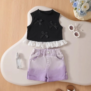 Flat lay of girl's summer set with black bow vest, lace hem and purple denim shorts