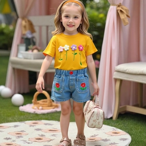 Detail of yellow cotton tee with 3D floral patches and embroidered denim shorts for girls