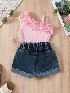 Ensemble d'été pour filles avec haut à volant rose et short en jean sur bois