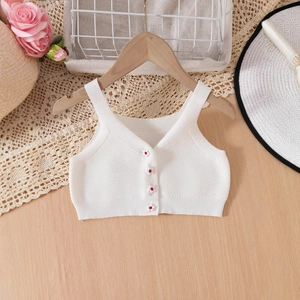 Dettaglio del gilet in maglia bianca per neonata con bottoni decorativi a fiori