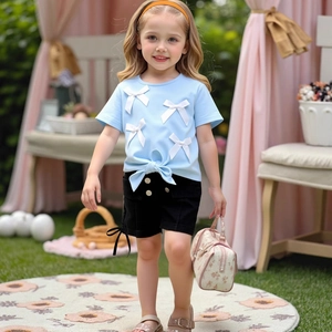 Detail of blue T-shirt with 3D white bows, tie-knot hem and buttoned black shorts