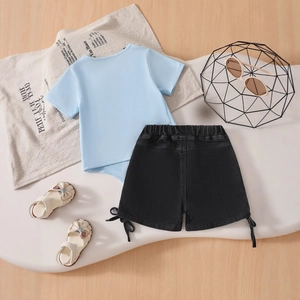 Flat lay of a blue bow-knot T-shirt and black shorts set with cute white bow sandals