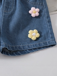 Detailed close-up of girls denim shorts featuring colorful handmade crochet flower accents